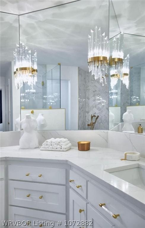 bathroom with a chandelier, vanity, and walk in shower