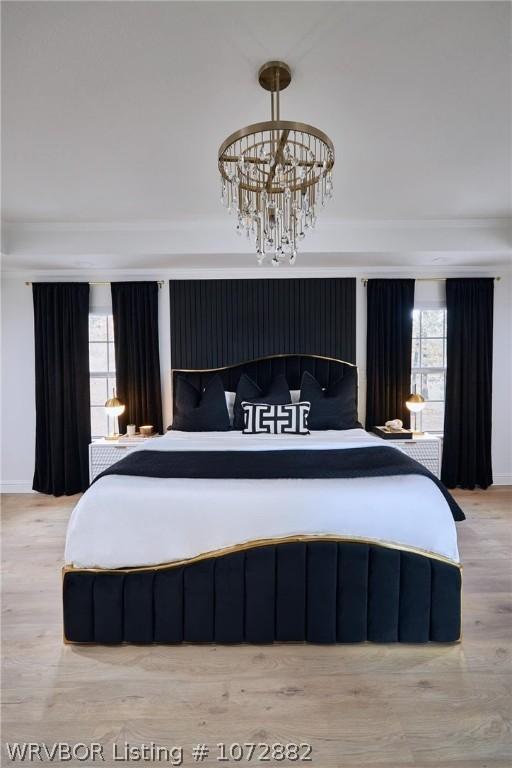 bedroom featuring light wood-type flooring, multiple windows, and a notable chandelier