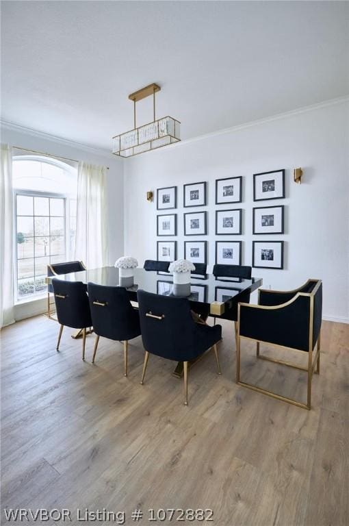 dining space featuring light hardwood / wood-style floors and crown molding