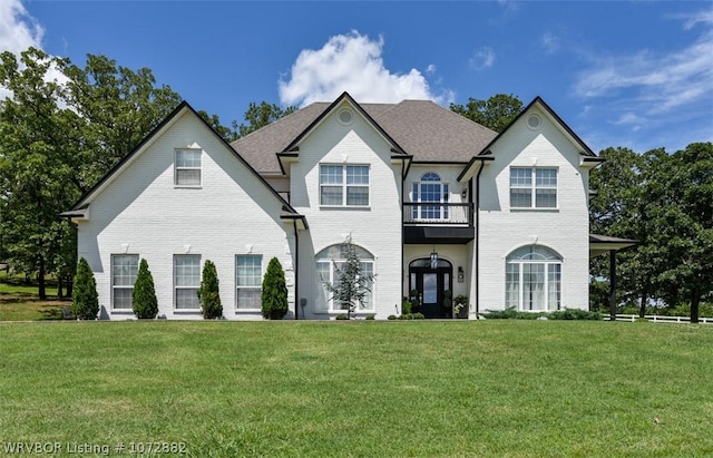 french provincial home featuring a balcony and a front lawn