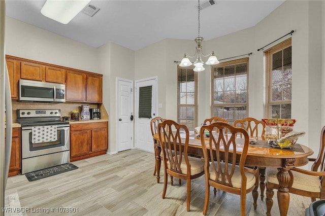 kitchen featuring light hardwood / wood-style flooring, an inviting chandelier, hanging light fixtures, stainless steel appliances, and decorative backsplash