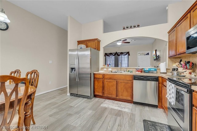 kitchen with ceiling fan, stainless steel appliances, sink, and decorative backsplash