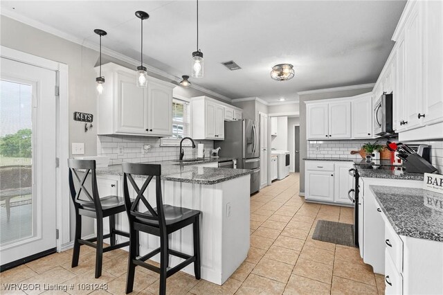 1205 S Division St, Lavaca, AR 72941 - kitchen with a peninsula, stainless steel appliances, a sink, decorative backsplash, and white cabinets