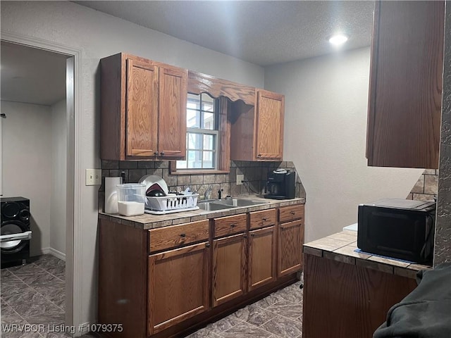 kitchen with tile counters, marble finish floor, backsplash, and a sink