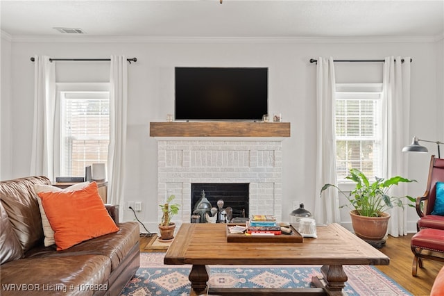 living room with hardwood / wood-style flooring, ornamental molding, a brick fireplace, and a wealth of natural light