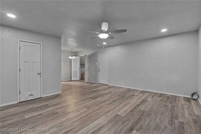 empty room with a ceiling fan, wood finished floors, baseboards, recessed lighting, and a textured ceiling