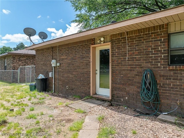 property entrance featuring brick siding and fence