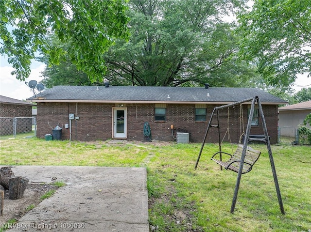 rear view of house featuring central AC unit, brick siding, and roof with shingles