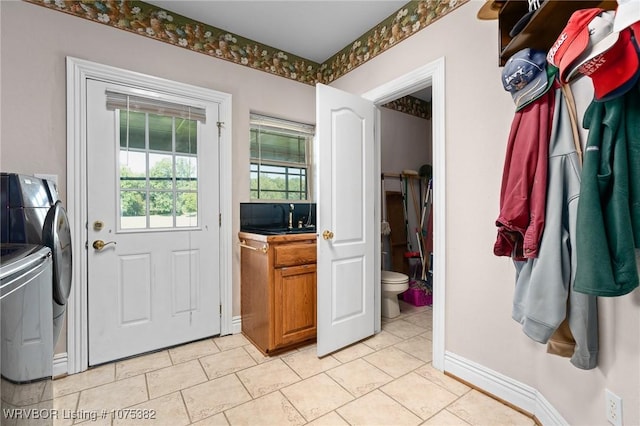 doorway to outside with light tile patterned floors, baseboards, and separate washer and dryer