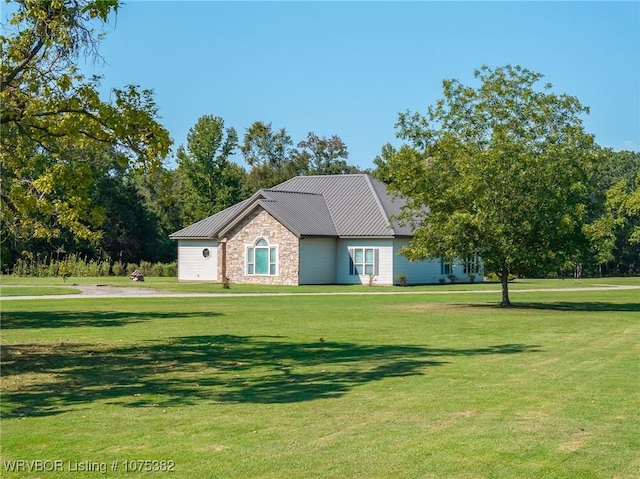 view of front of property featuring metal roof, a front lawn, and stone siding