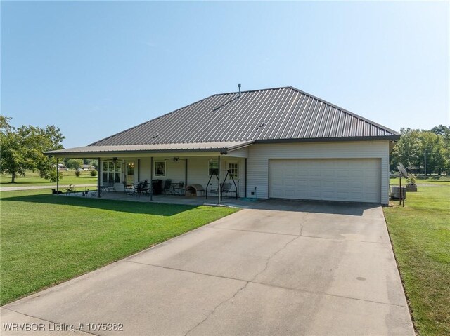 view of front facade featuring a ceiling fan, an attached garage, metal roof, and a front lawn