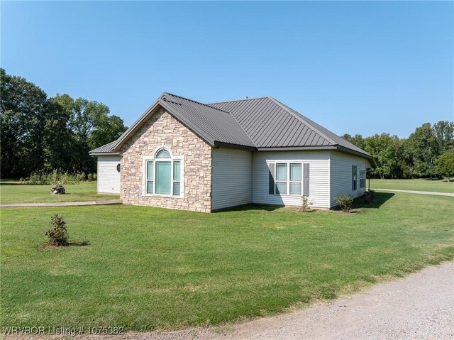 view of property exterior featuring metal roof, a yard, and stone siding