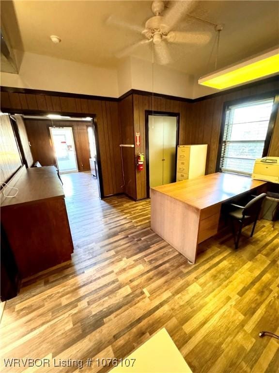 interior space with light wood-type flooring, butcher block countertops, ceiling fan, and wooden walls