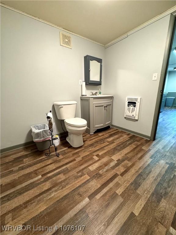 bathroom with vanity, heating unit, crown molding, hardwood / wood-style floors, and toilet