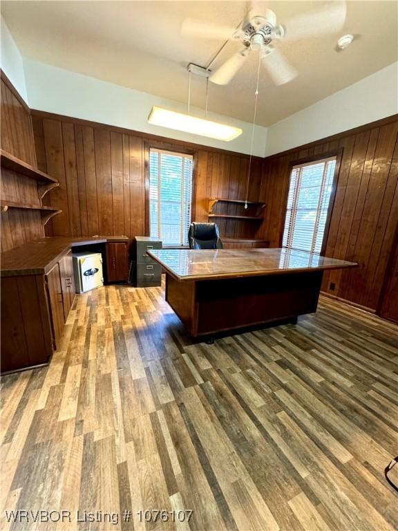 unfurnished office with wooden walls, ceiling fan, and hardwood / wood-style flooring