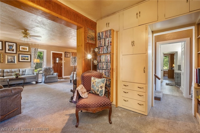 living area with light colored carpet, a textured ceiling, and ceiling fan