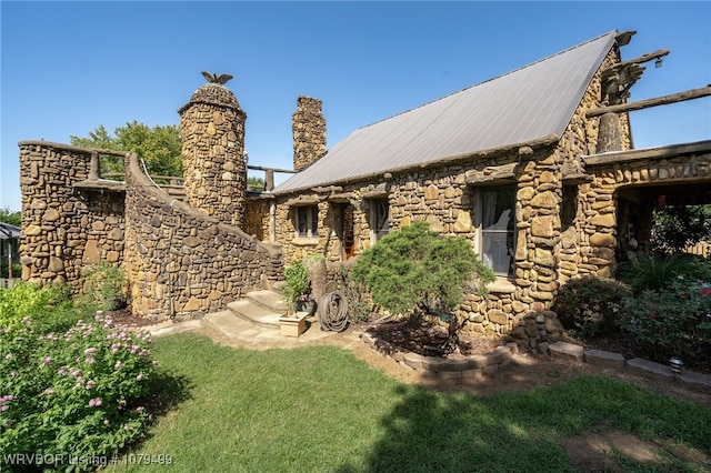 view of property exterior featuring stone siding, a chimney, and metal roof