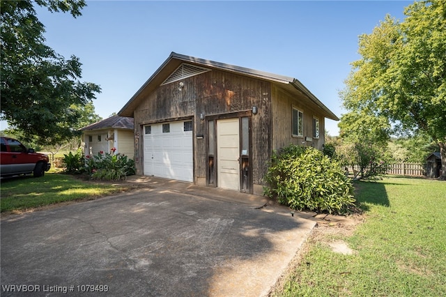 view of home's exterior with a lawn, a garage, and fence