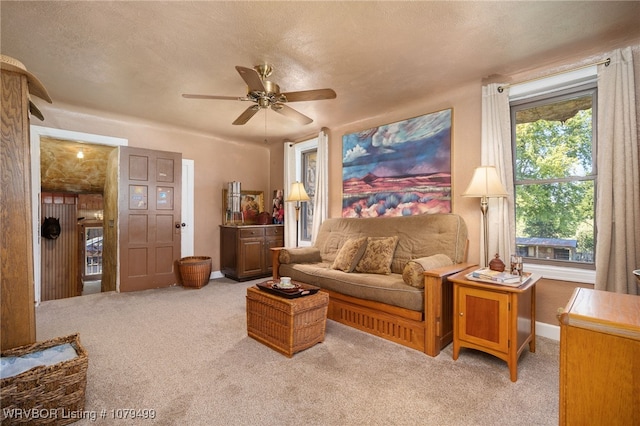 living area with baseboards, carpet, ceiling fan, and a textured ceiling