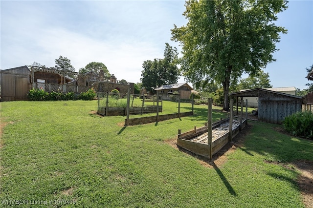 view of yard with an outbuilding, a shed, fence, and a garden