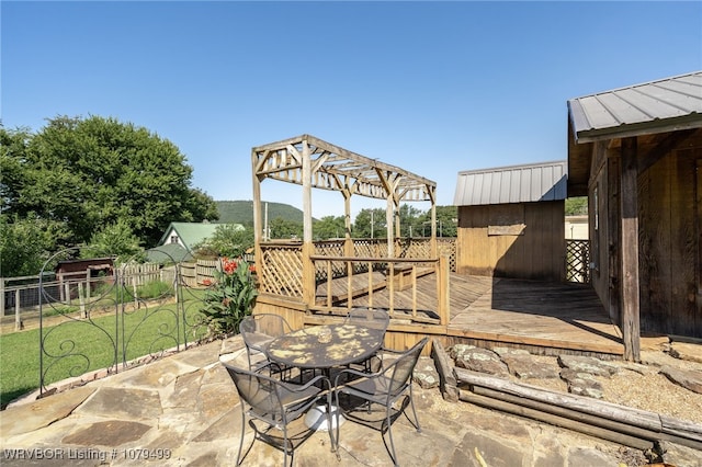 view of patio / terrace featuring outdoor dining space, an outbuilding, a deck, and a shed