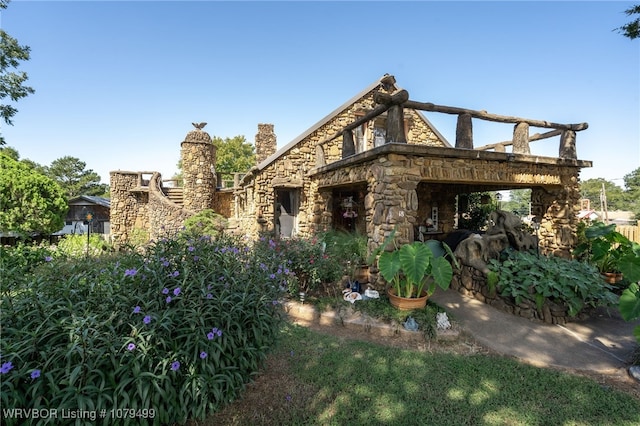 view of front of home with stone siding and a chimney