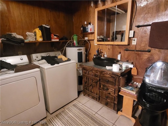 laundry area featuring light tile patterned floors, electric water heater, separate washer and dryer, and wood walls