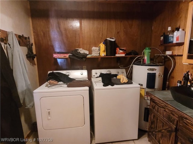 laundry area featuring washing machine and dryer, electric water heater, sink, and wooden walls