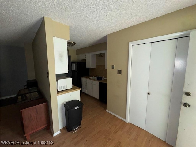 412 7th St, Barling, AR 72923 - kitchen featuring freestanding refrigerator, light wood finished floors, white cabinetry, a textured ceiling, and light countertops