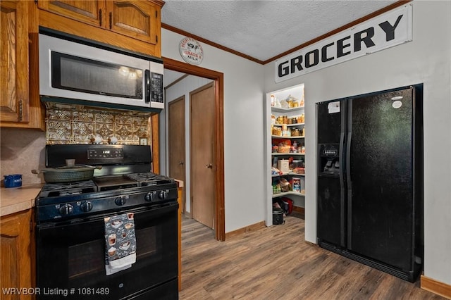 2650 Spielerville Rd, Paris, AR 72855 - kitchen with black appliances, ornamental molding, brown cabinetry, light countertops, and dark wood-type flooring