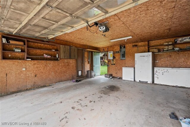 2650 Spielerville Rd, Paris, AR 72855 - garage featuring a garage door opener, electric panel, and freestanding refrigerator