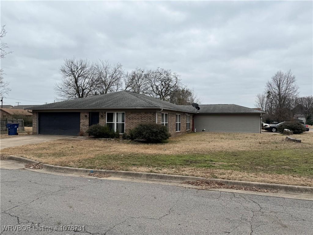 single story home featuring driveway, a garage, roof with shingles, a front lawn, and brick siding