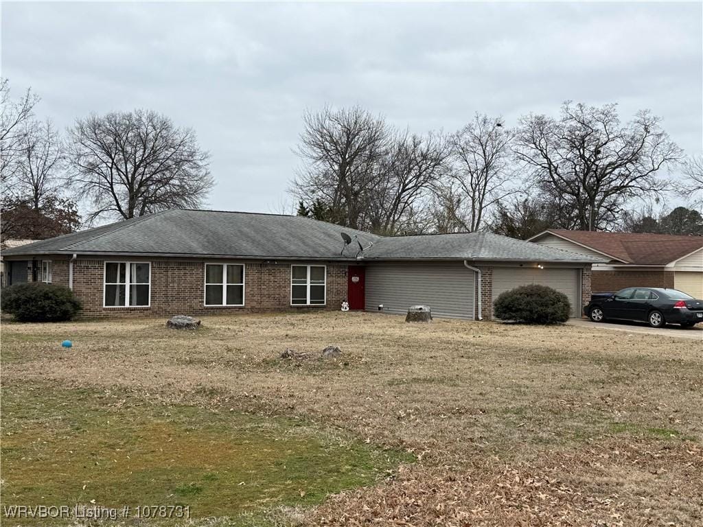 ranch-style home featuring a garage, brick siding, and a front lawn