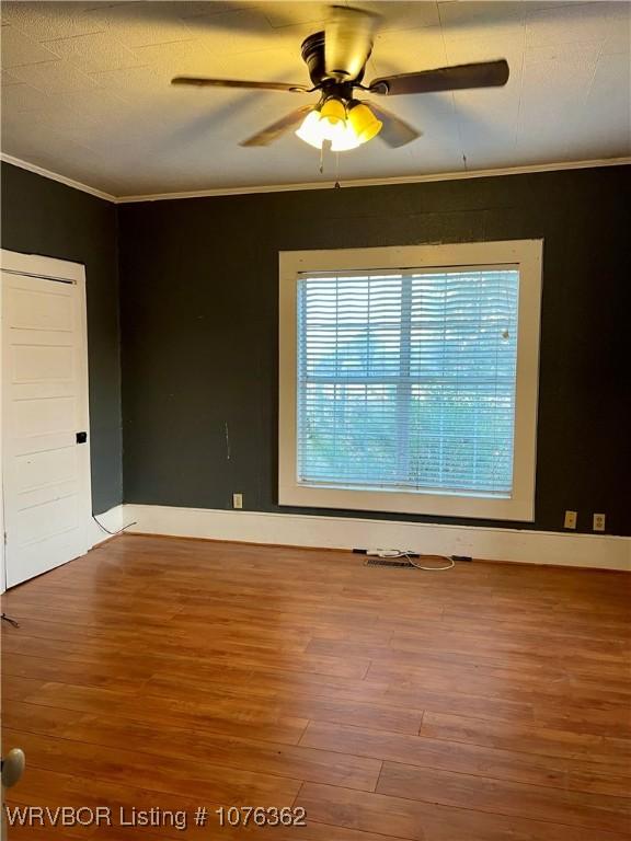 unfurnished room with ceiling fan, wood-type flooring, and crown molding