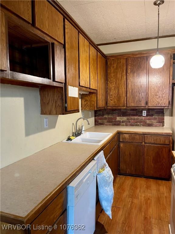 kitchen featuring pendant lighting, dishwasher, crown molding, sink, and light hardwood / wood-style floors