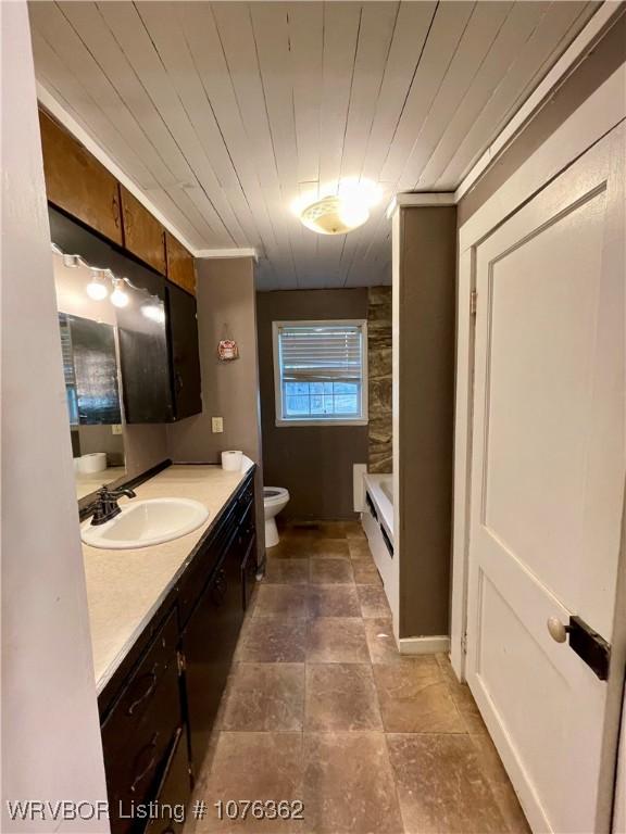 bathroom with a bathing tub, vanity, toilet, and wooden ceiling