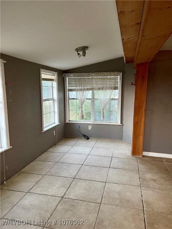 unfurnished room featuring light tile patterned flooring and vaulted ceiling