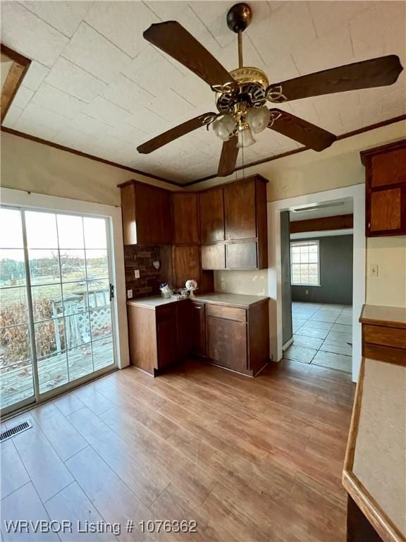 kitchen with tasteful backsplash, ceiling fan, crown molding, and light wood-type flooring