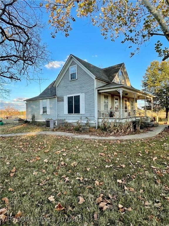 back of property with a lawn and covered porch