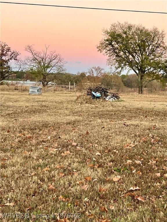 yard at dusk featuring a rural view