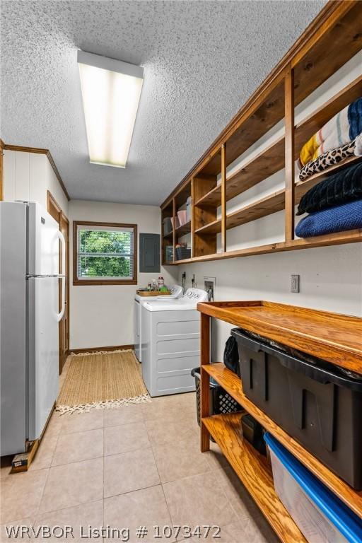 laundry room featuring washing machine and clothes dryer, electric panel, and light tile patterned floors