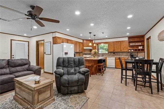 living room with ceiling fan, light tile patterned floors, a textured ceiling, and ornamental molding