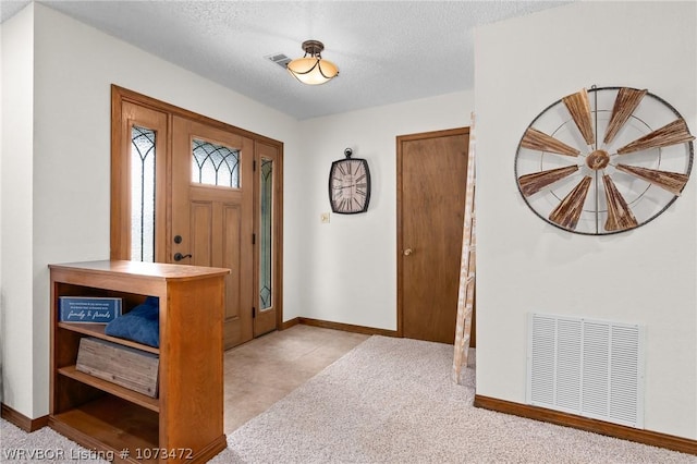 carpeted foyer with a textured ceiling