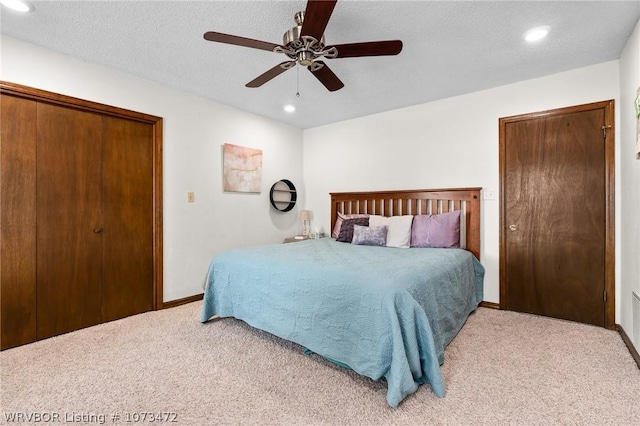 carpeted bedroom with ceiling fan, a textured ceiling, and a closet