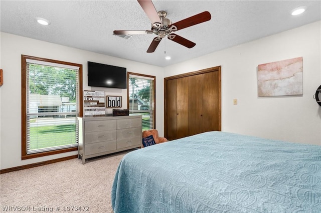 bedroom with light carpet, a textured ceiling, multiple windows, and ceiling fan