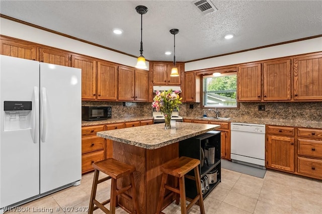 kitchen with a kitchen bar, white appliances, sink, decorative light fixtures, and a center island