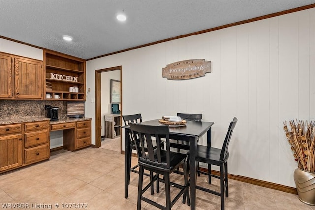 tiled dining area with a textured ceiling, built in desk, and crown molding