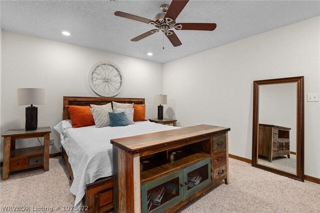 bedroom with ceiling fan, light colored carpet, and a textured ceiling