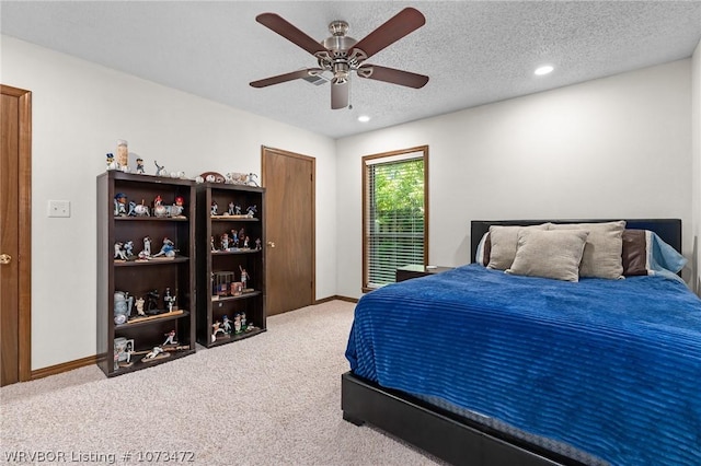 bedroom featuring a textured ceiling, light colored carpet, and ceiling fan