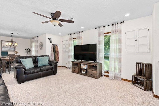 carpeted living room with a textured ceiling and ceiling fan with notable chandelier